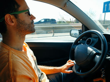 Young man sitting in car on sunny day