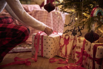 Person wrapping present under christmas tree