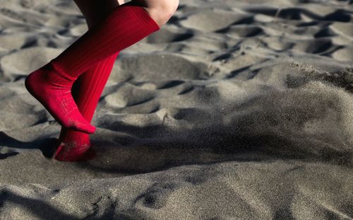 Low section of woman running on sand at beach