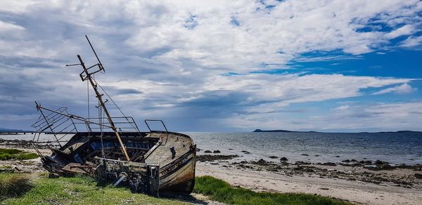 Abandoned ship on beach against sky