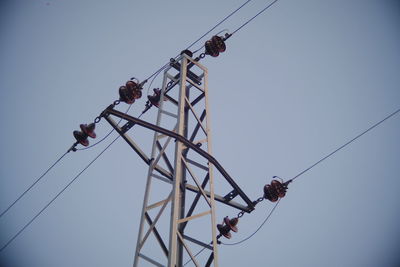 Low angle view of bird perching on electricity pylon against clear sky