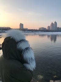 Rear view of man on river by buildings against sky