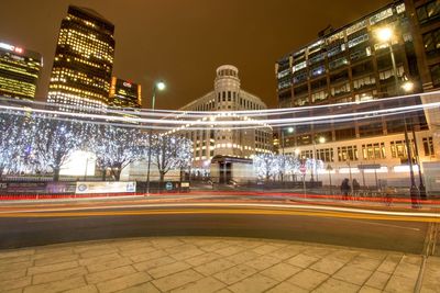 Light trails on road against buildings at night