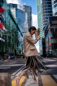 Side view of young woman walking on street in city