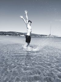 Woman splashing water in sea against sky
