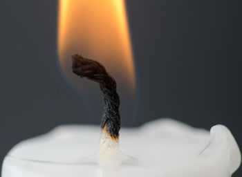 Close-up of burning candle against gray background