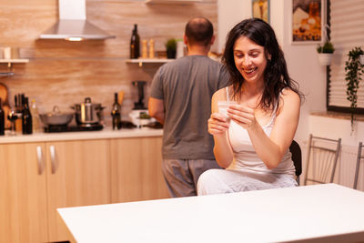 Portrait of young woman using mobile phone while sitting in cafe