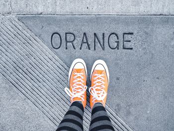 Low section of woman standing on footpath with text 