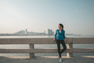 Full length portrait of young woman standing against sea