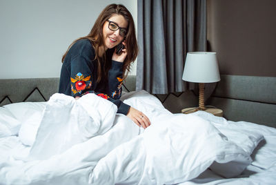 Young woman sitting on bed at home