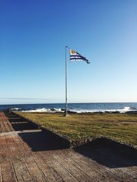 Flag on beach against clear blue sky