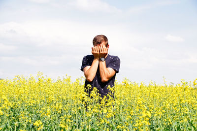 Man standing amidst yellow flowers on oilseed rape field