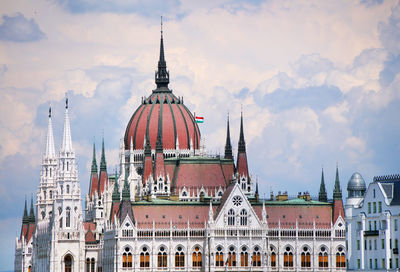 Low angle view of hungarian parliament building against cloudy sky in city