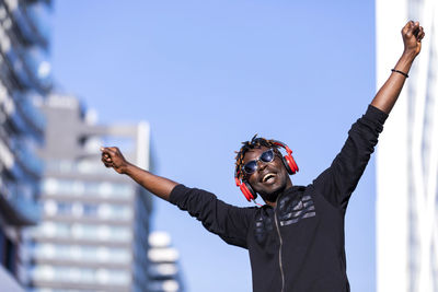 Low angle view of happy man standing against sky