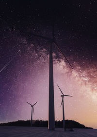 Low angle view of silhouette wind turbines against sky at night