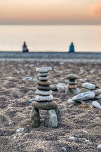 Stack of stones on beach against sky during sunset