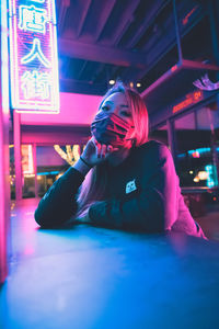 Woman looking away while sitting on illuminated stage