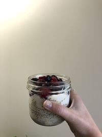 Close-up of hand holding glass jar against white background