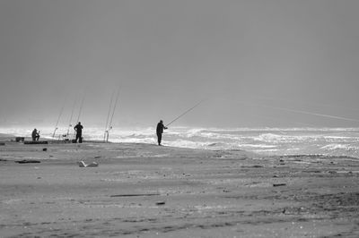 People at beach against clear sky