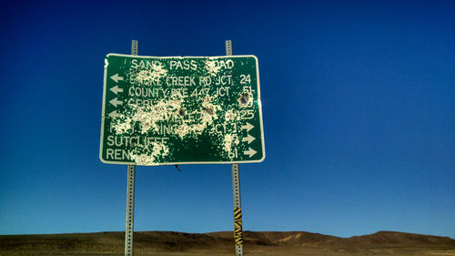 Low angle view of road sign against clear blue sky