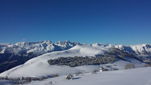 Scenic view of snowcapped mountains against clear blue sky