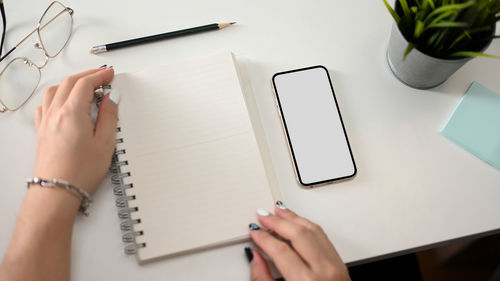 Midsection of woman writing in book at table