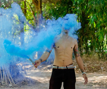 Shirtless man holding smoke bomb on field