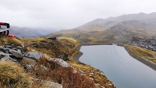 Scenic view of river by mountains against sky