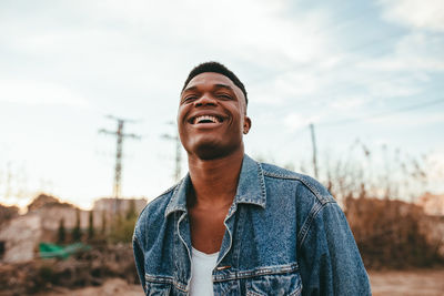 Portrait of smiling young man standing against sky