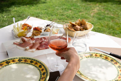 Cropped image of hand holding wine glass with antipasto served on table