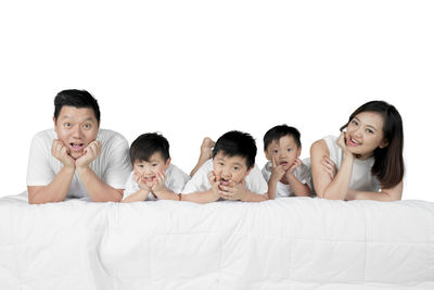 Portrait of family lying on bed against white background