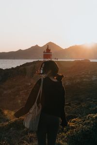 Rear view of woman standing on shore against sky