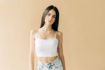 Portrait of young woman standing against pink background