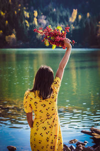 Rear view of woman standing by lake