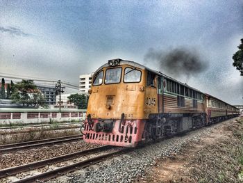 Train on railroad track against cloudy sky