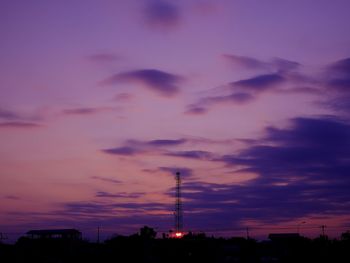 Silhouette communications tower against sky at dusk