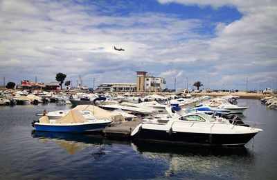 Boats moored at harbor against sky