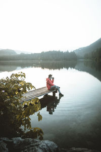 High angle view of woman drinking coffee while sitting by lake 