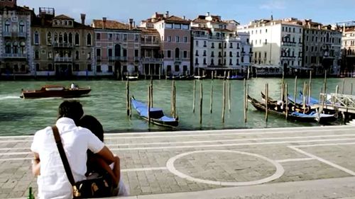 Rear view of men sitting on boat in city