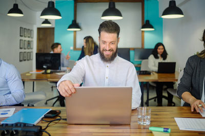 Smiling businessman looking at laptop at office