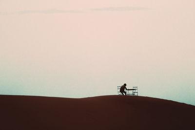 Silhouette men standing on desert against sky