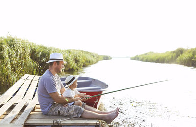 Man sitting in lake against sky