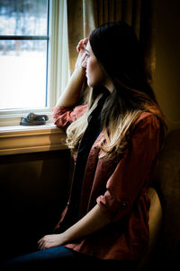 Young woman looking through window 