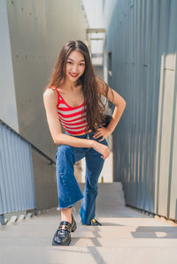 Full length of young woman standing against wall