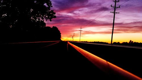 Silhouette of railroad tracks against sky during sunset