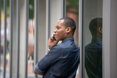 Portrait of young man standing by window