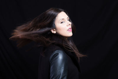 Side view of woman looking away with windswept hair against black background