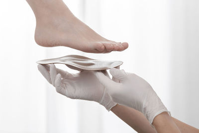 Cropped hand of doctor holding insoles by patient feet