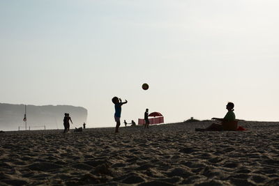 People playing with ball on beach