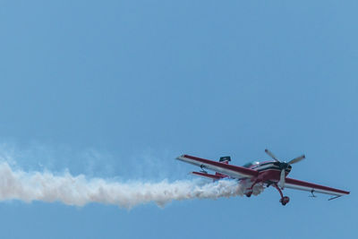 Low angle view of airplane flying against clear blue sky